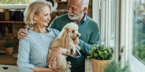 Uśmiechnięta para seniorów trzyma pudla. Idealny pies dla seniora, który wnosi radość i towarzystwo.