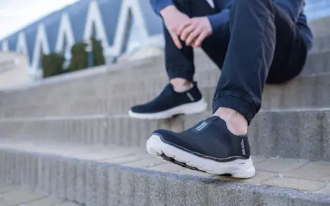 Czarne, wsuwane buty sportowe na białej podeszwie, idealne jako buty dla seniorów, zapewniające komfort i stabilność na schodach.