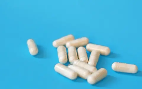 Kapsułki na niebieskim tle. Mogą symbolizować skutki uboczne leków na prostatę, które wpływają na codzienne życie.