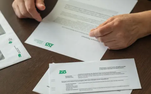 Dłonie przeglądają dokumenty ZUS. Czy to czas na emeryturę, kiedy przejść?