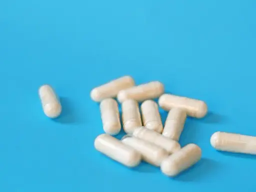 Kapsułki na niebieskim tle. Mogą symbolizować skutki uboczne leków na prostatę, które wpływają na codzienne życie.