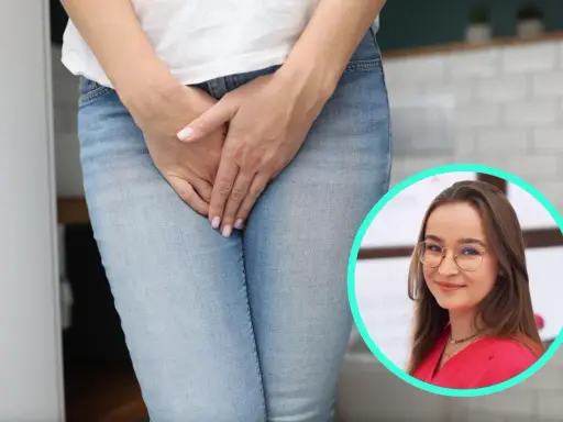 Kobieta w dżinsach, z dłońmi na kroku, w tle kobieta w okularach. Temat: sikanie podczas sexu.