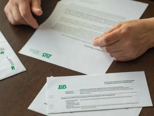 Dłonie przeglądają dokumenty ZUS. Czy to czas na emeryturę, kiedy przejść?
