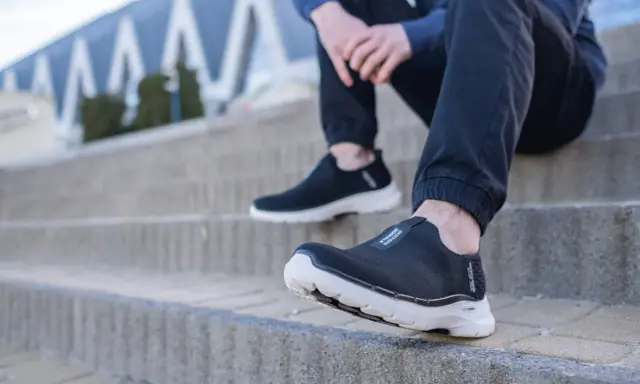 Czarne, wsuwane buty sportowe na białej podeszwie, idealne jako buty dla seniorów, zapewniające komfort i stabilność na schodach.