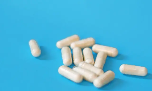 Kapsułki na niebieskim tle. Mogą symbolizować skutki uboczne leków na prostatę, które wpływają na codzienne życie.