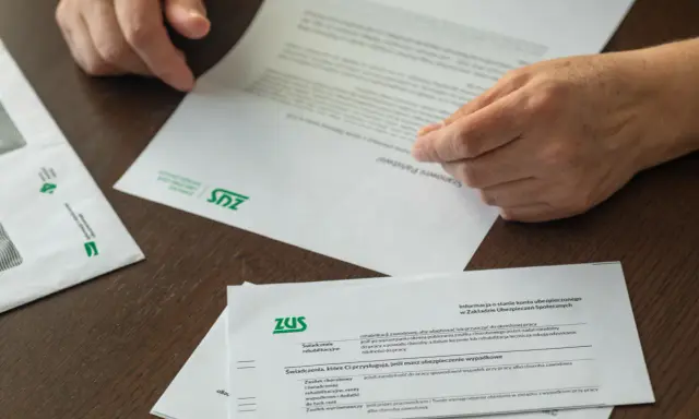 Dłonie przeglądają dokumenty ZUS. Czy to czas na emeryturę, kiedy przejść?