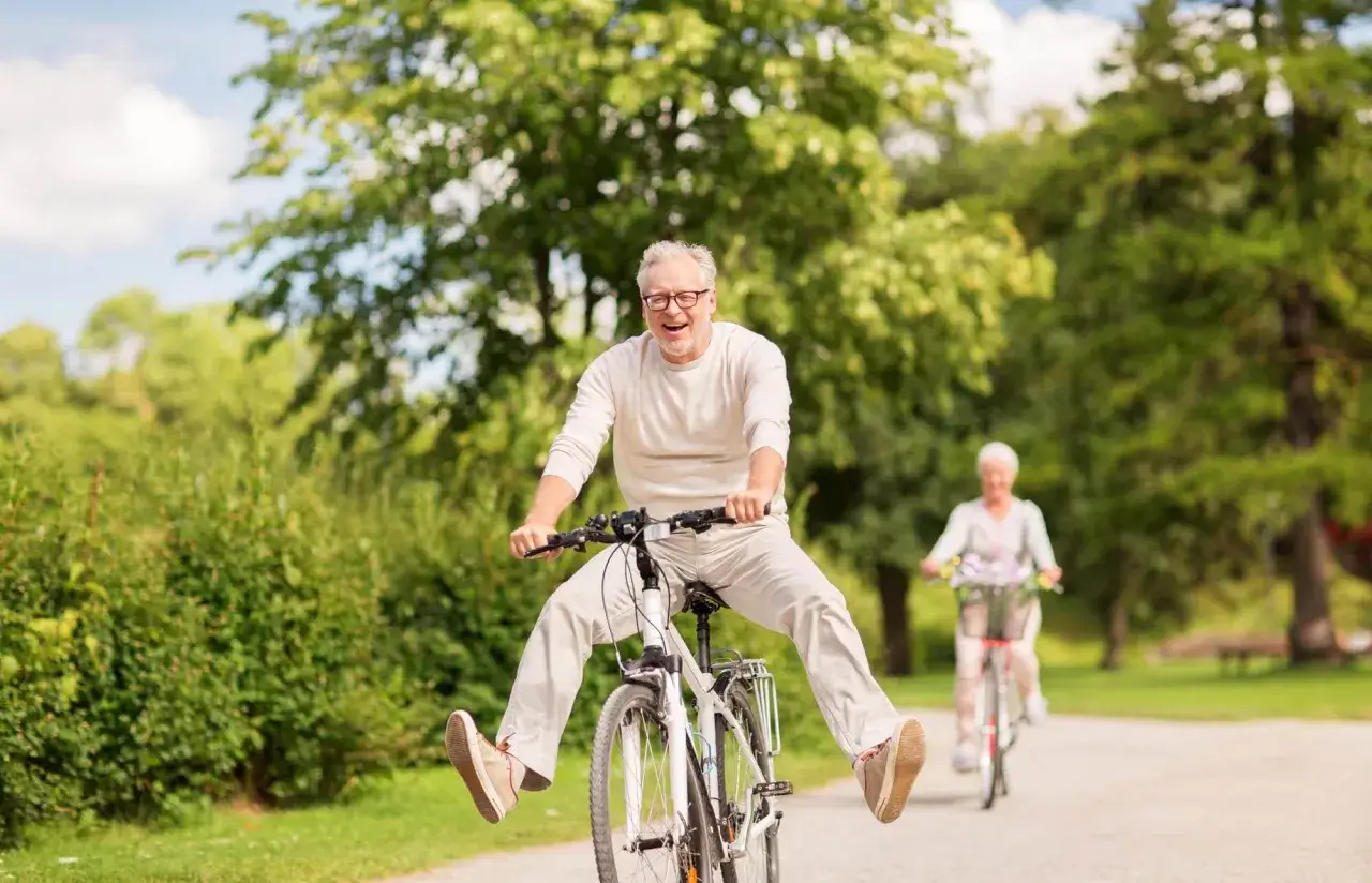 Szczęśliwi seniorzy na rowerach w parku. Wspaniały spos&oacute;b, by dowiedzieć się, co robić na emeryturze i cieszyć się aktywnością na świeżym powietrzu.